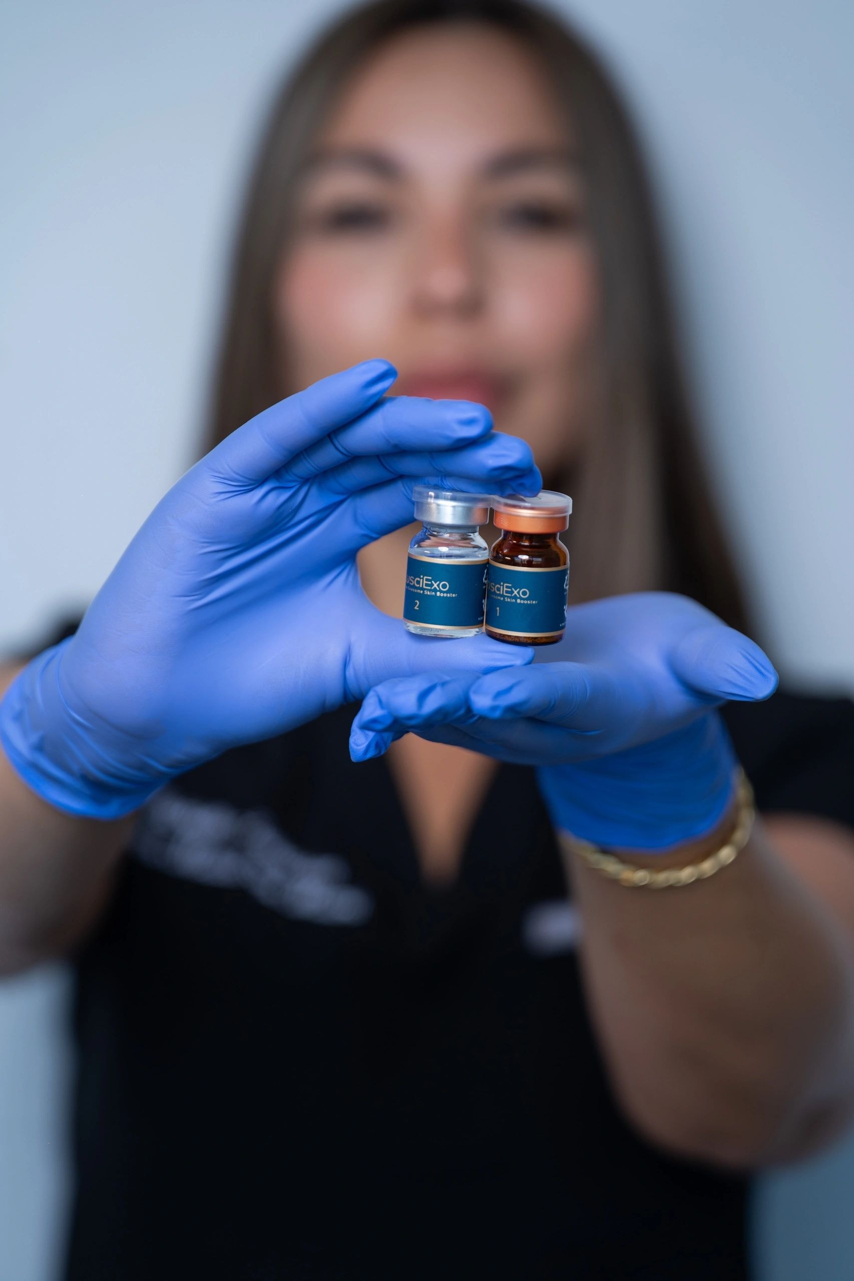 Gloved hands holding premium skincare product vials